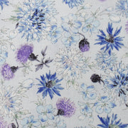 a close-up view of a fabric with a floral pattern. The pattern consists of various blue and purple flowers, including daisies, chrysanthemums, and other types of flowers, all arranged in a visually appealing manner. The flowers are depicted in different sizes and orientations, creating a sense of depth and movement in the fabric. The overall design is vibrant and eye-catching, making it an attractive choice for clothing or home decor.