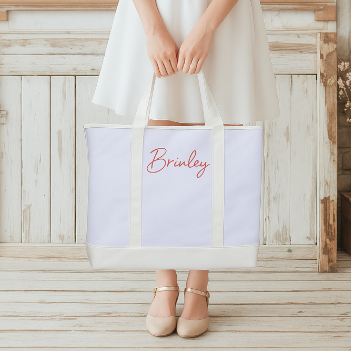 A person is holding a large white tote bag with the name "Brineley" printed on it.