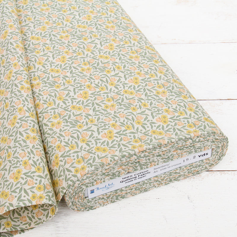 a roll of fabric with a floral print pattern, placed on a white wooden surface.
