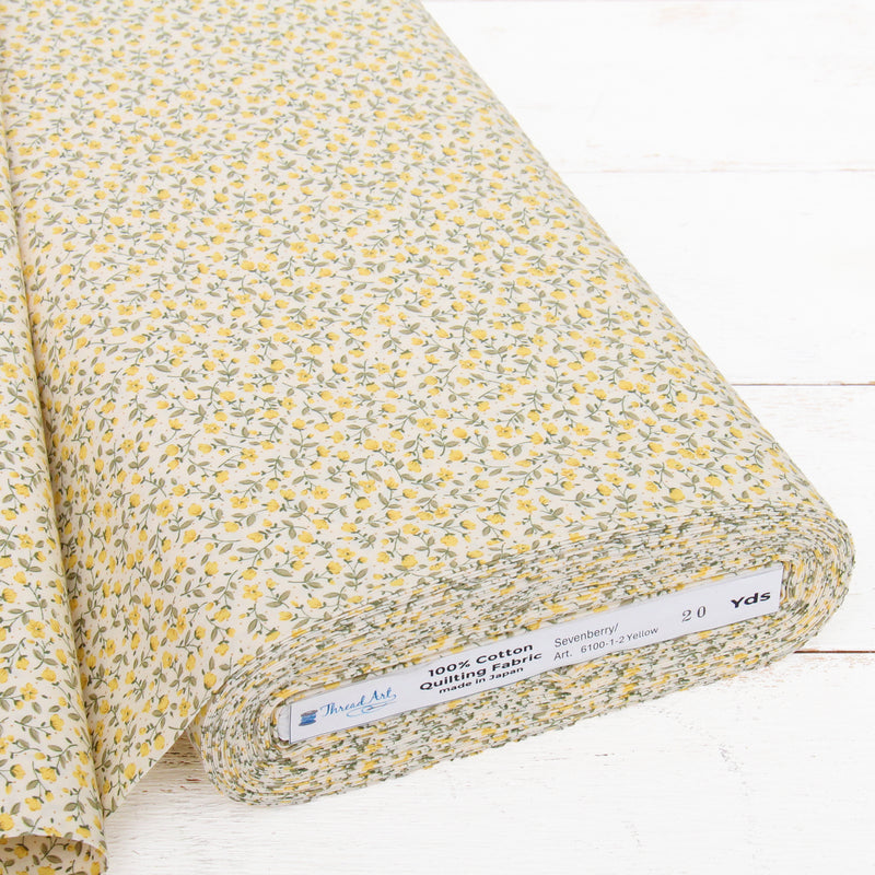 A roll of fabric with a yellow and green floral print pattern, displayed on a white surface.