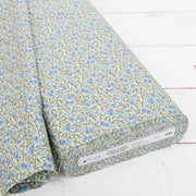 a roll of fabric with a floral pattern in shades of green and blue.