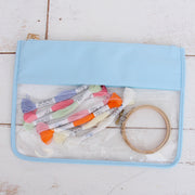 Light blue clear zipper pouch bag holding embroidery floss skeins and a wooden hoop