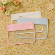Pastel pink, blue, and white clear zipper pouch bags on a floral fabric background