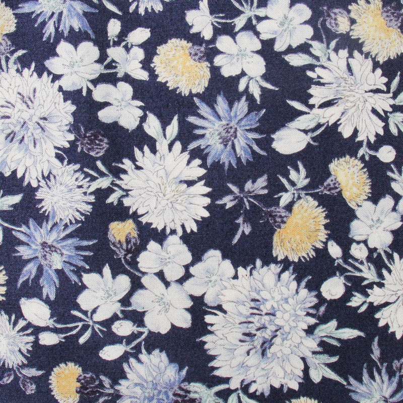 a close-up view of a fabric with a floral pattern. The fabric has a dark blue background with white and yellow flowers and leaves scattered throughout, creating a visually appealing and vibrant design.