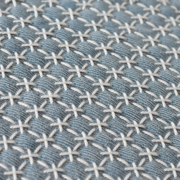 White cross-stitch sashiko pattern on blue linen
