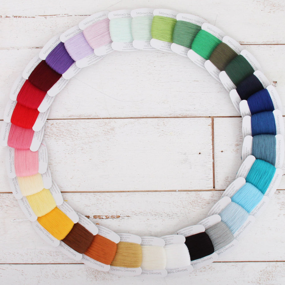 Ring of 32 ThreadArt sashiko thread cards in every color on white wood