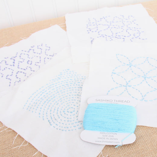 Sashiko sampler squares in blue and lavender with a turquoise thread card