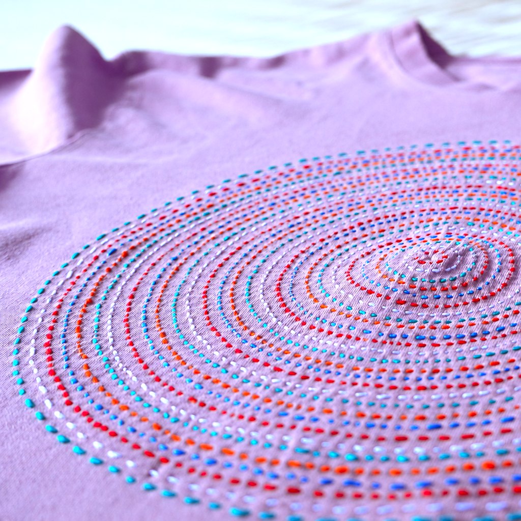 Concentric circles of colorful sashiko stitches on a lavender shirt