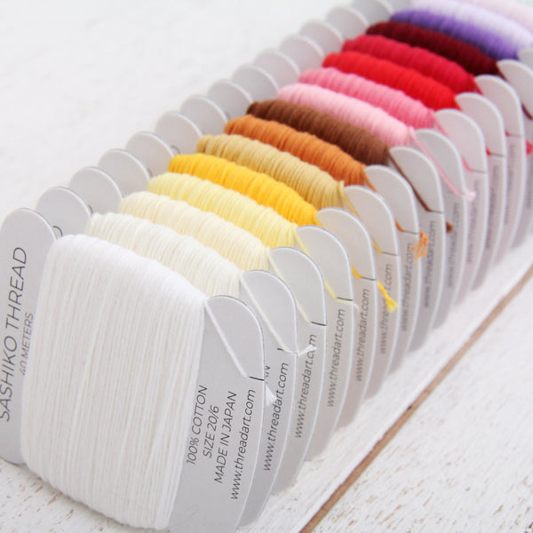 Row of sashiko thread cards in white, yellow, orange, pink, and red
