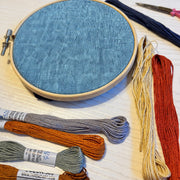 Blue yarn dyed linen fabric in an embroidery hoop with ThreadArt embroidery floss