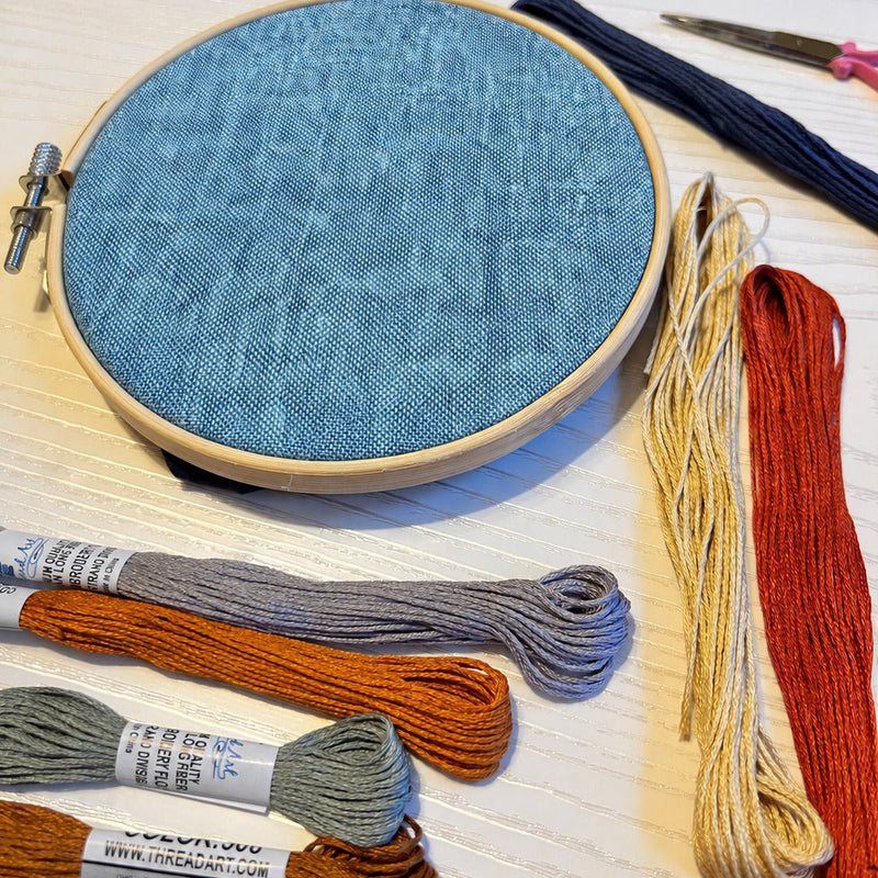 Blue yarn dyed linen fabric in an embroidery hoop with ThreadArt embroidery floss